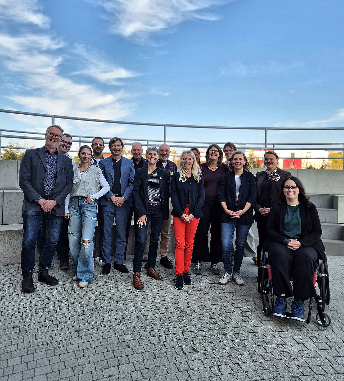 Die Beiratsmitglieder stehen für ein Gruppenfoto im Außenbereich bei blauem Himmel zusammen.