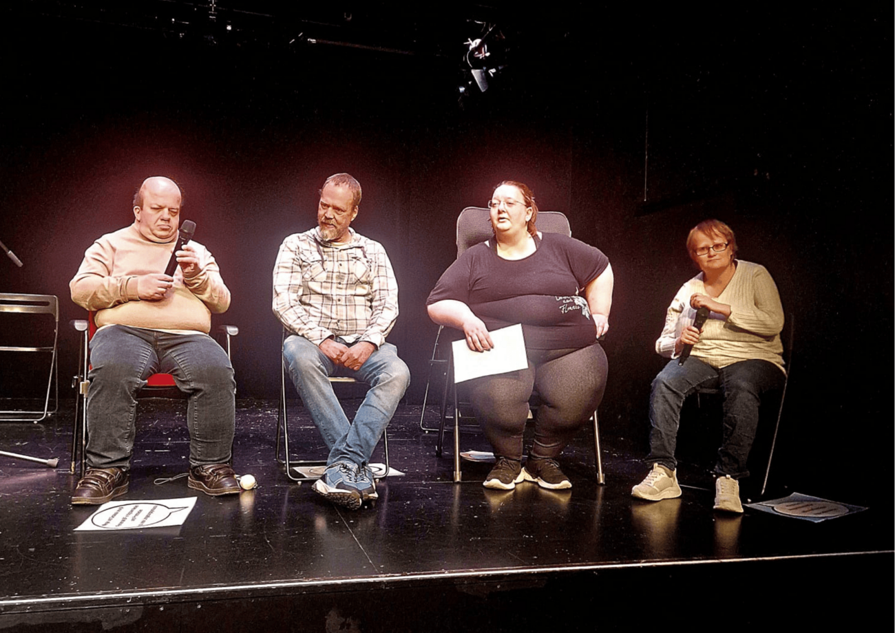 Vier Bildungsfachkräfte sitzen auf einer Theaterbühne