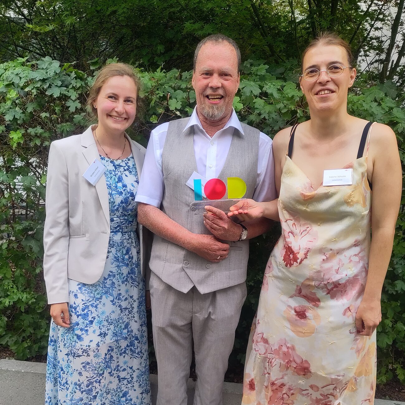 Drei Personen mit dem Award im Außenbereich